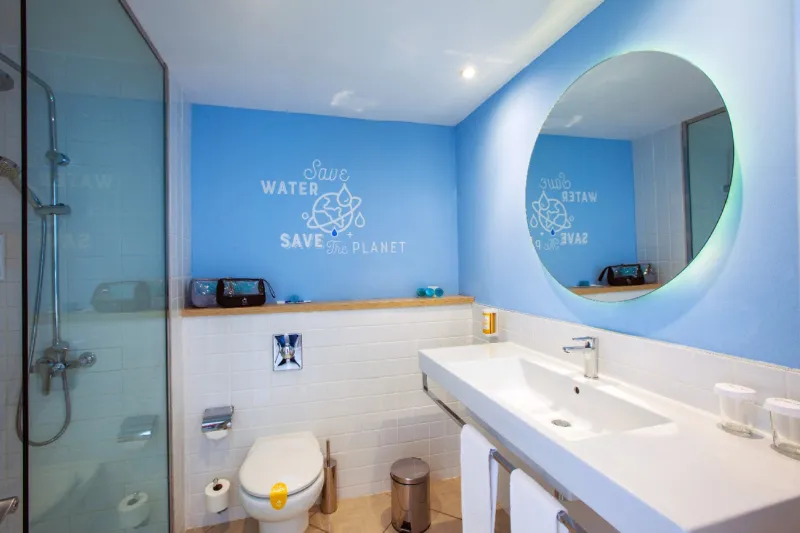Bathroom with a washbasin, a round illuminated mirror and a shower