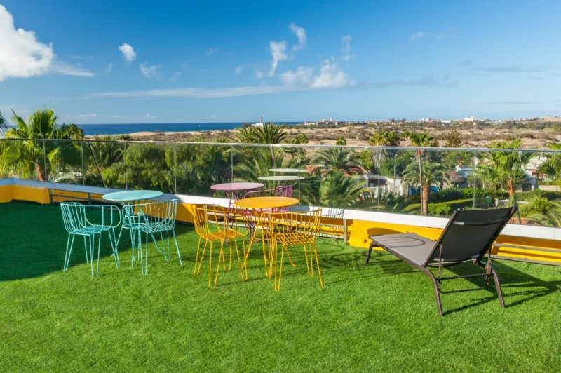 Lawn terrace with colourful tables and views of the Maspalomas dunes and the sea