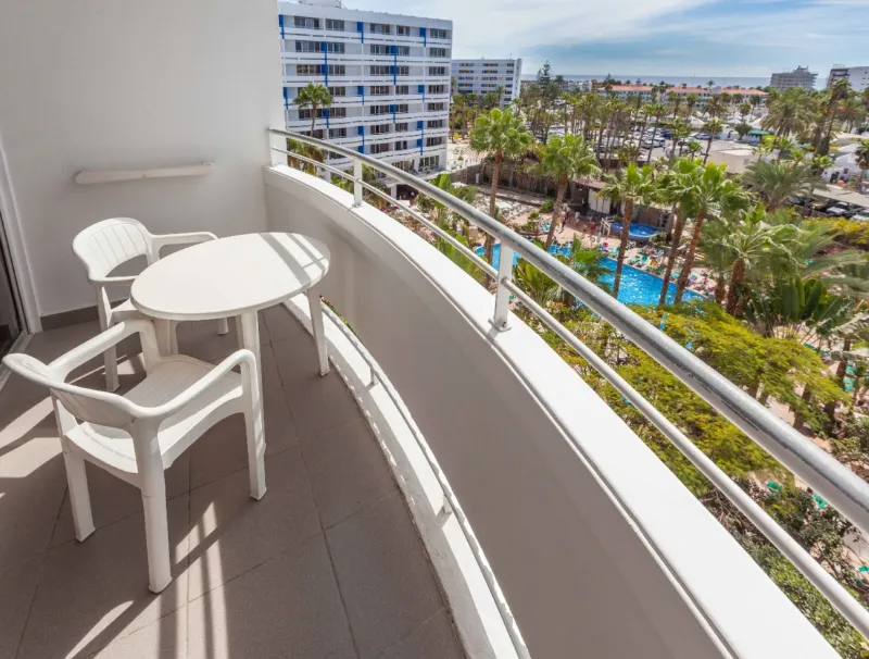 Balcony with a table and chairs overlooking the gardens and the pool
