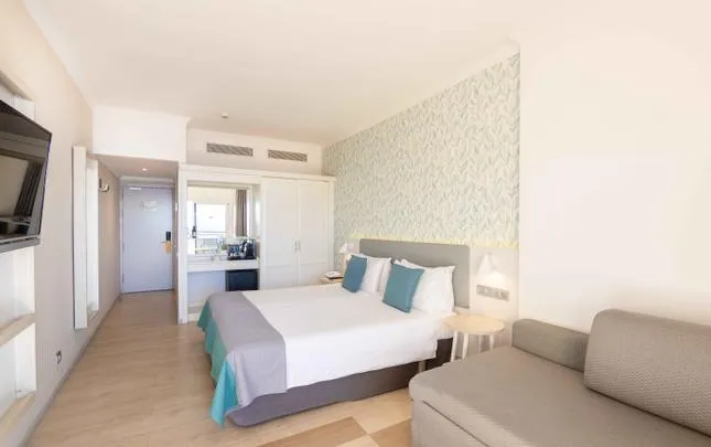Double room with a sofa and leaf-patterned wallpaper
